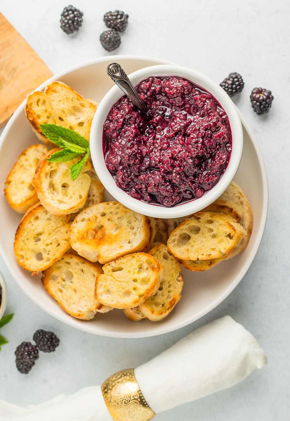 a white plate with baguettes and a white bowl of blackberry compote.