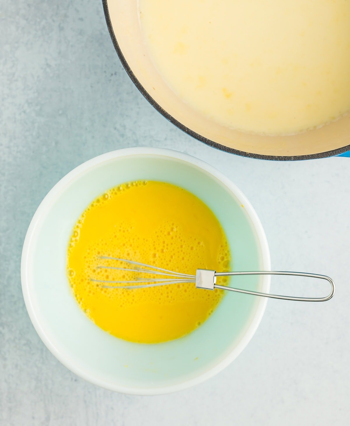 a bowl of eggs with a whisk in it.