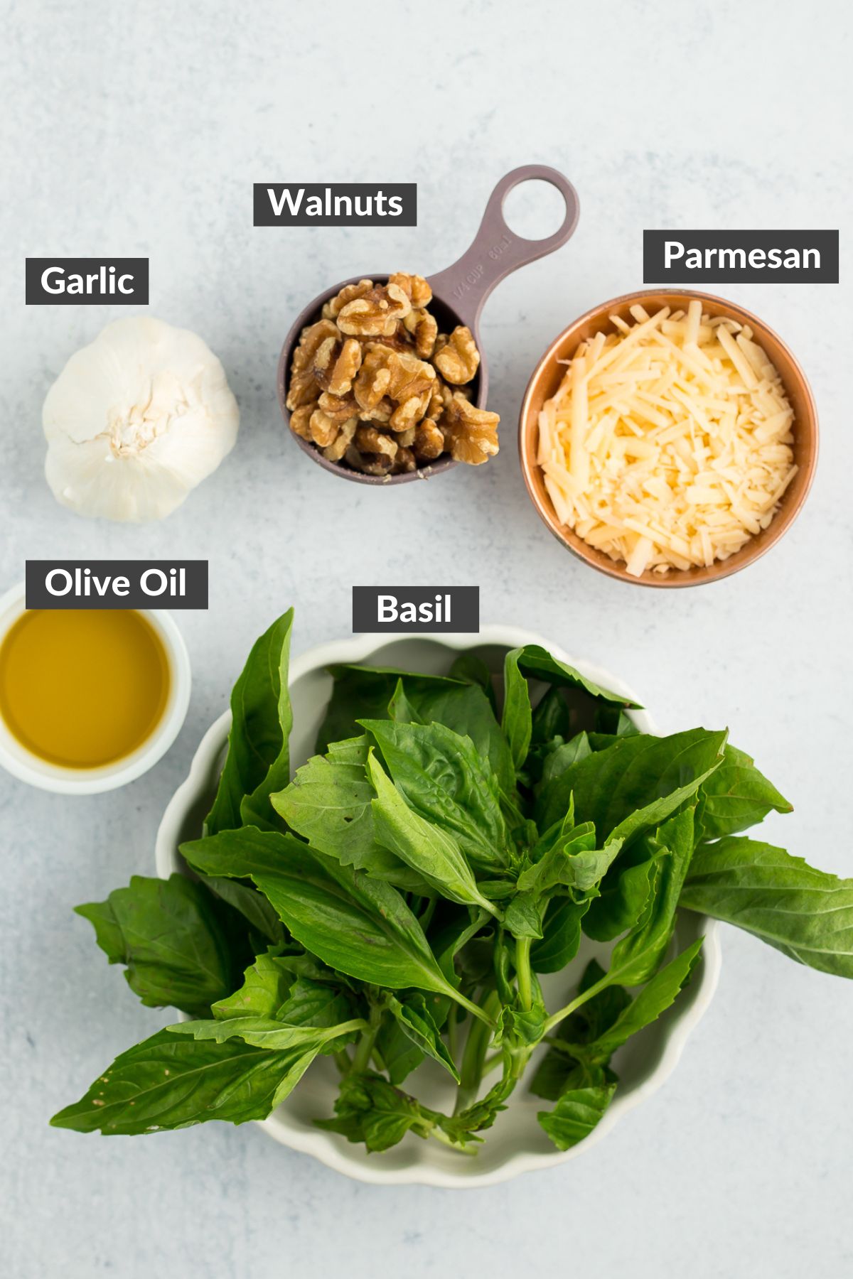 basil, walnuts, and other ingredients on a grey board.