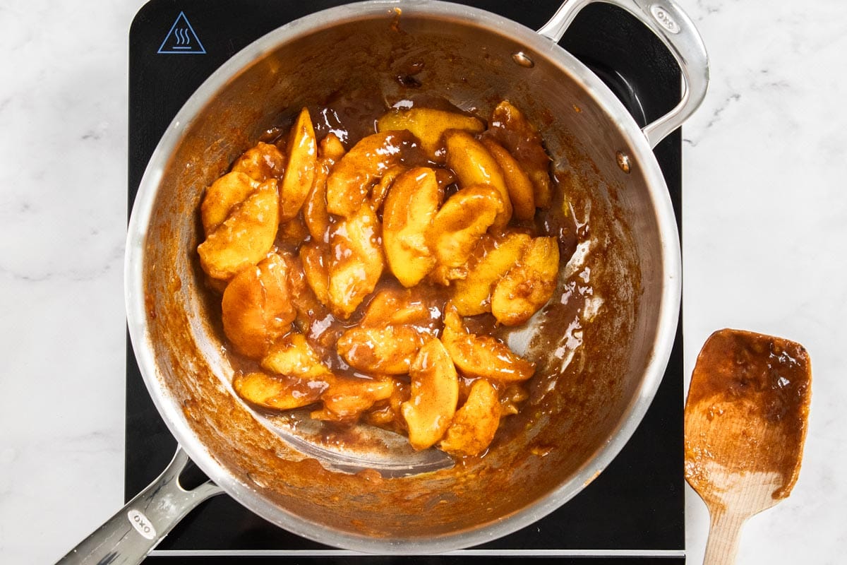 sliced peaches in a skillet being cooked.