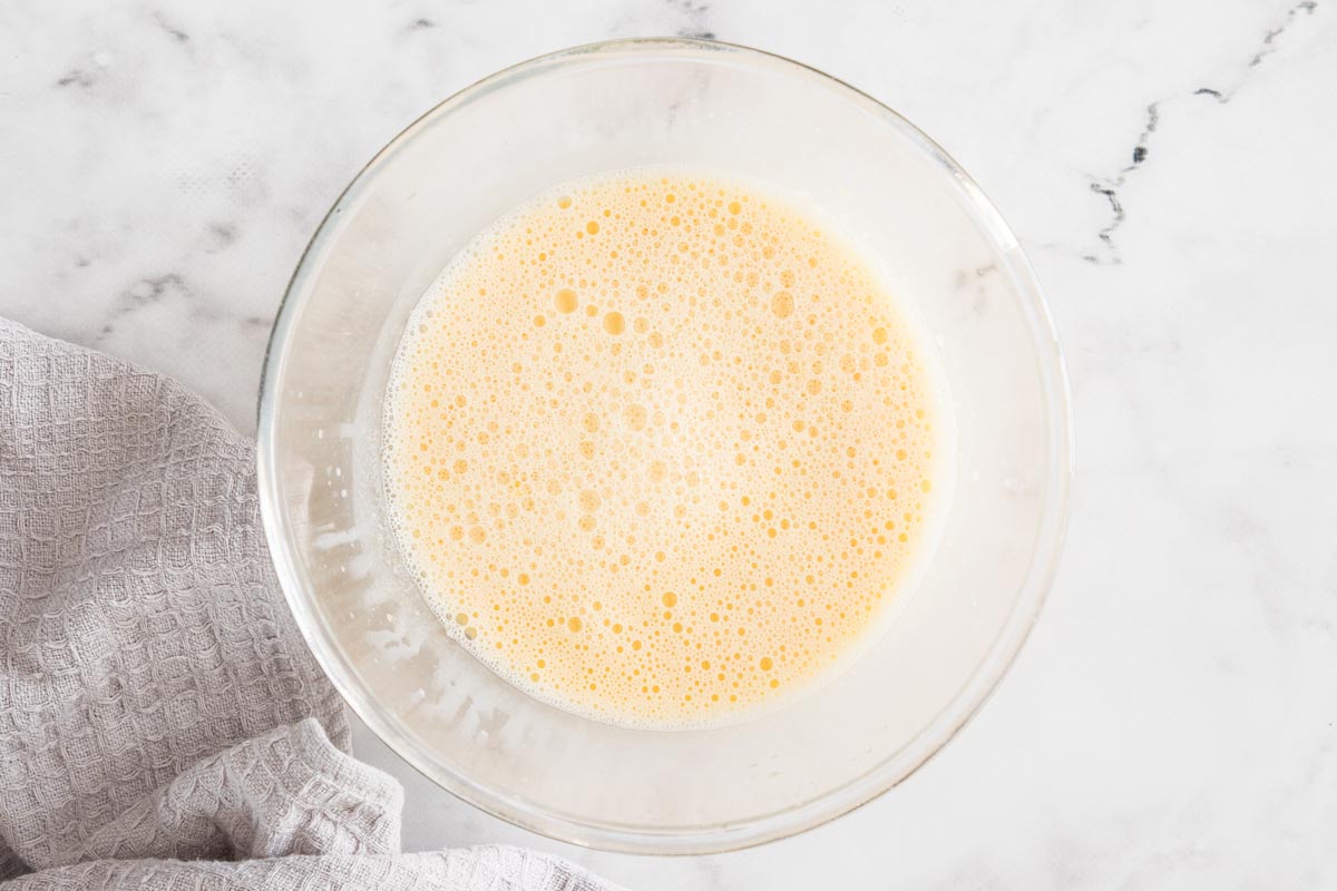 egg yolks and heavy cream whisked in a glass bowl.