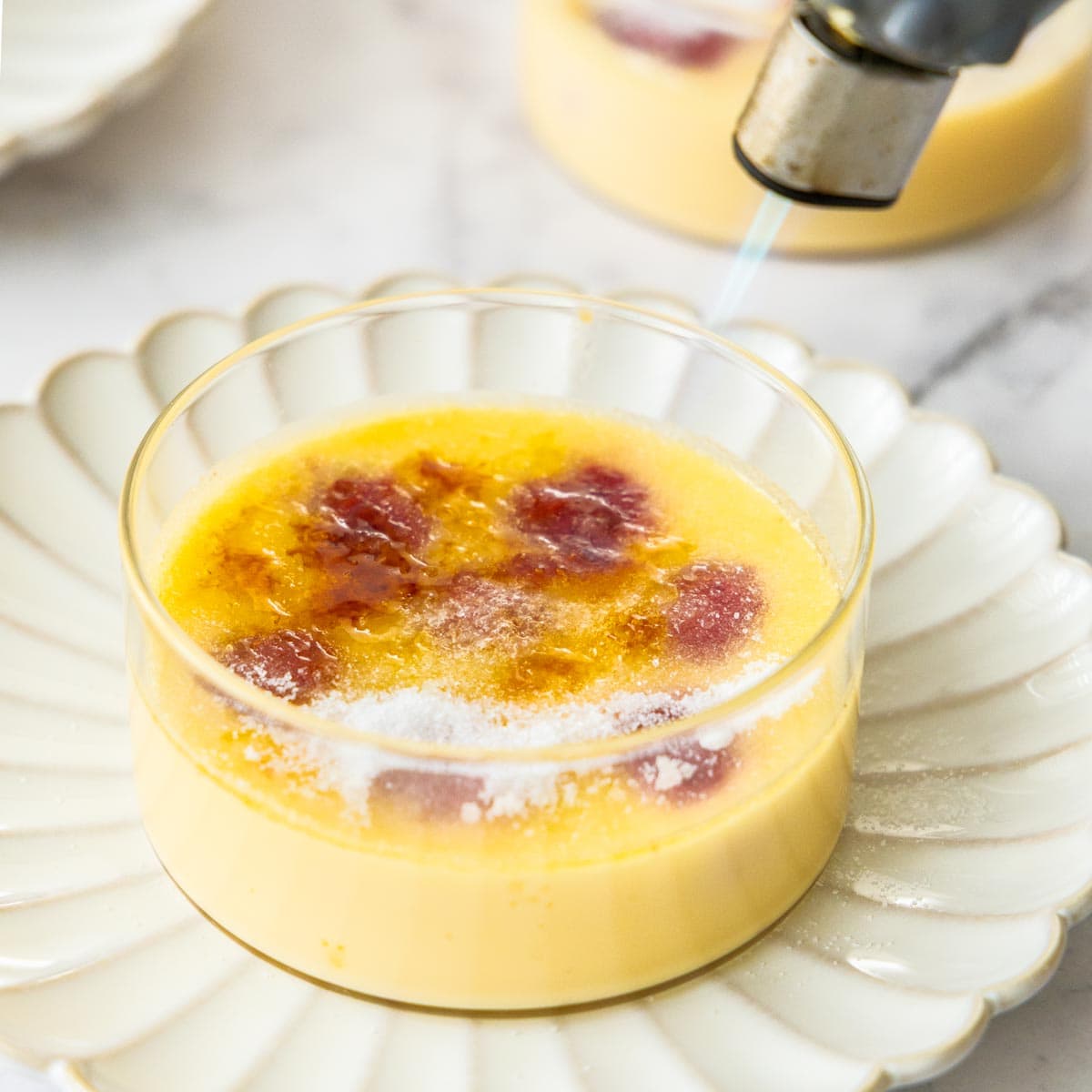 a kitchen torch caramelizing sugar on top of a custard.