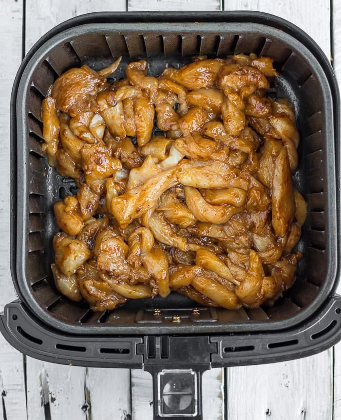 sliced chicken in an air fryer basket.