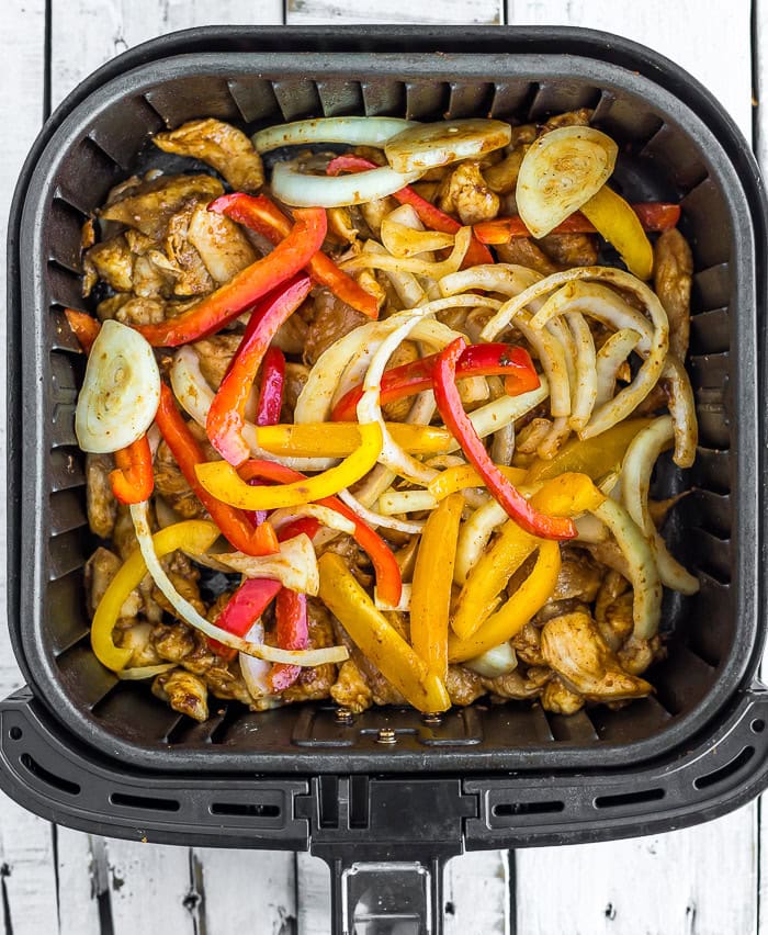 strips of peppers and onions on top of strips of chicken.