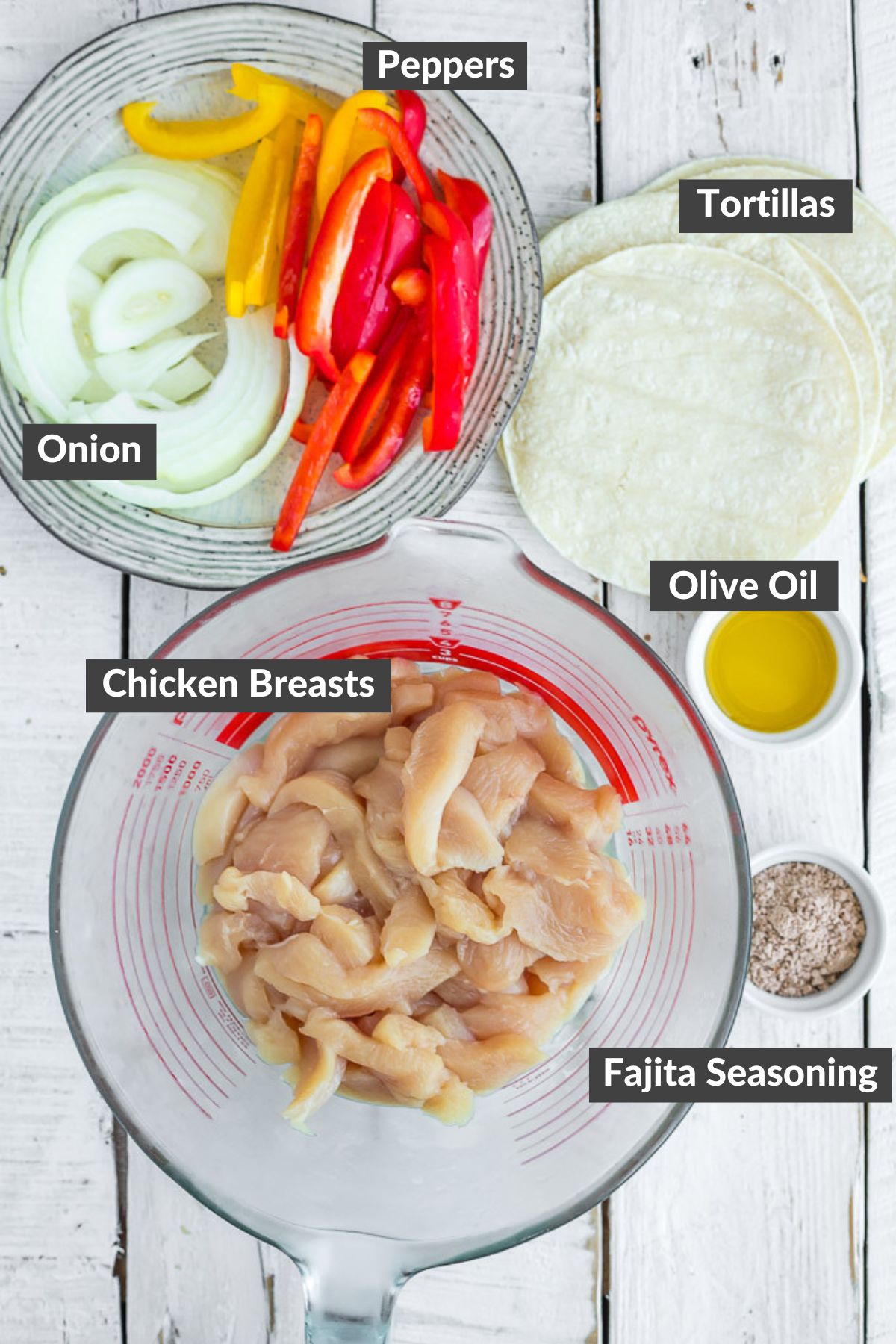 peppers, onions, tortillas, sliced chicken, and other ingredients on a wooden board.