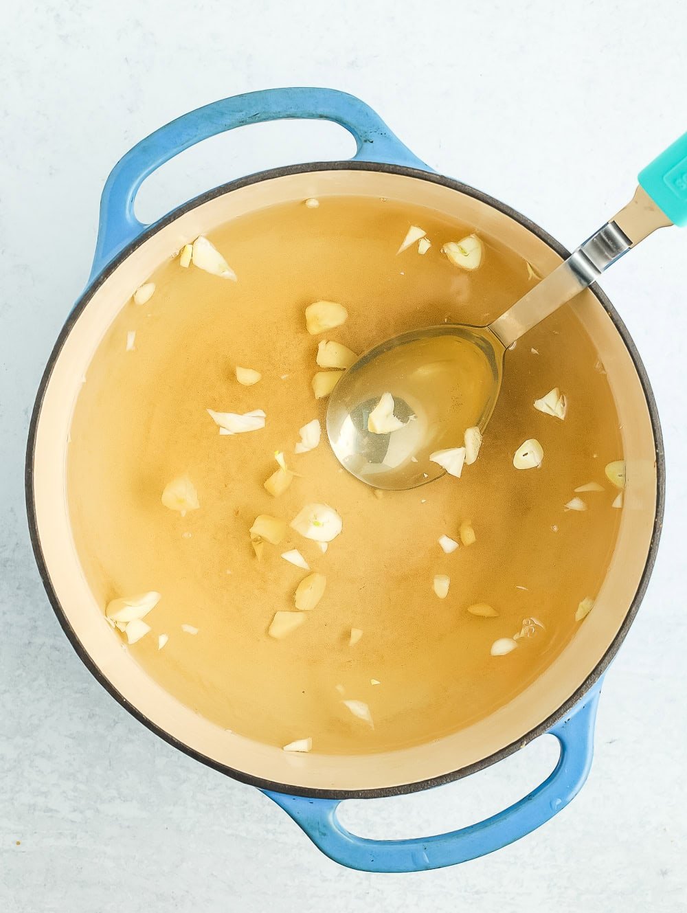 minced garlic and liquid in a blue Dutch oven.
