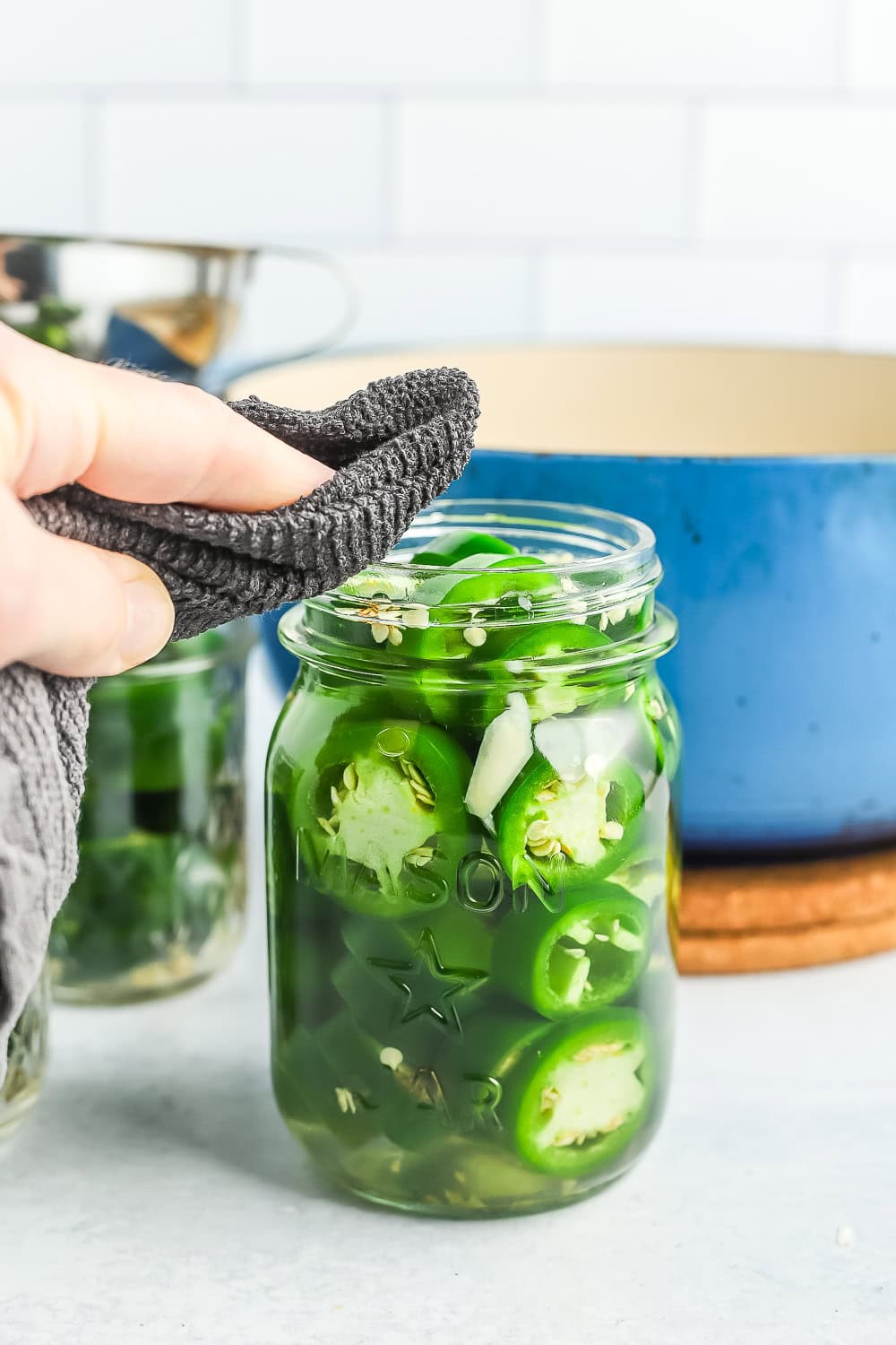 a rag wiping the rim of a canning jar.