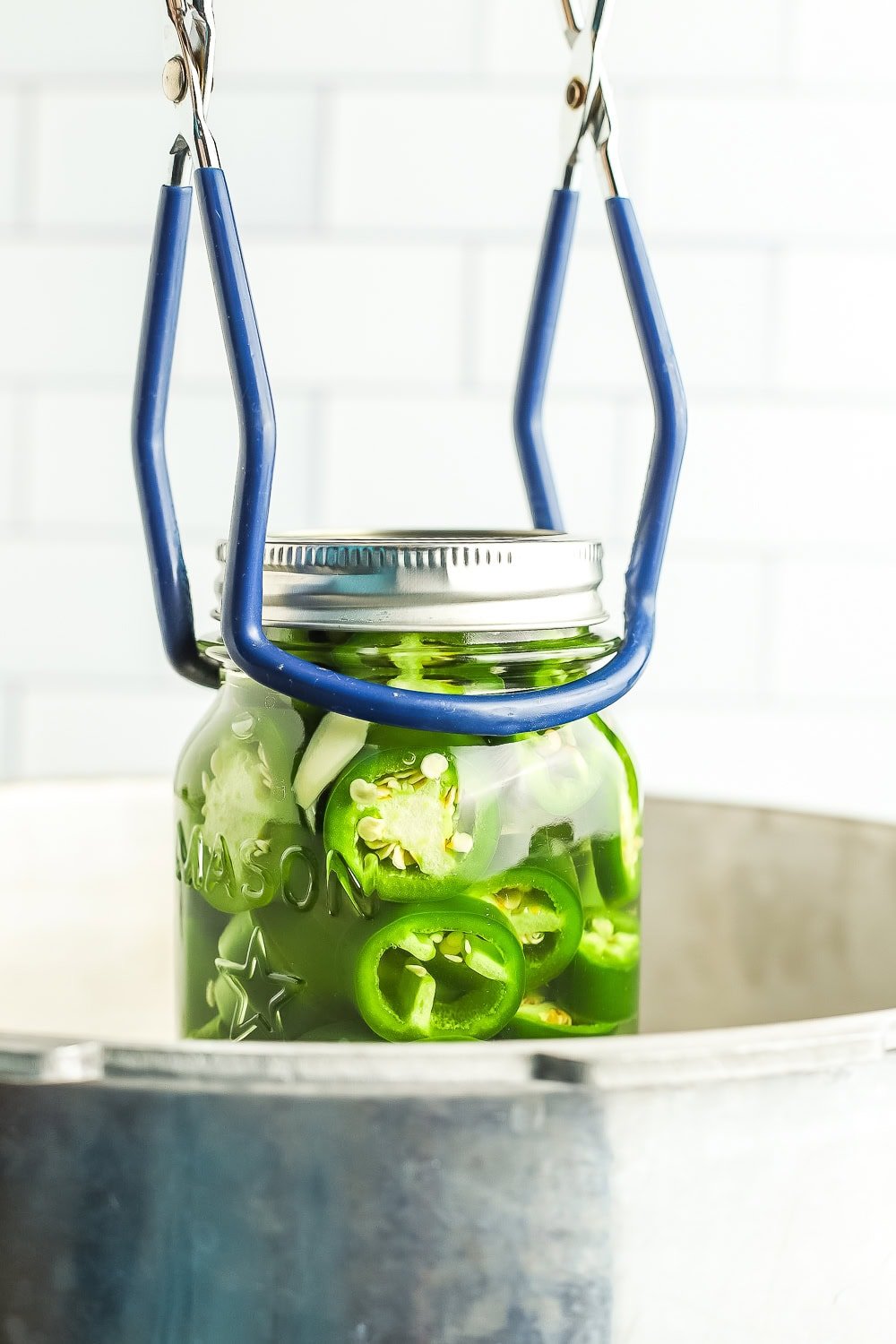 canning tongs putting a jar into a canner.
