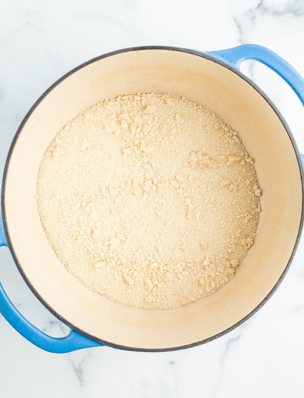 a blue Dutch oven with clumps of sugar.