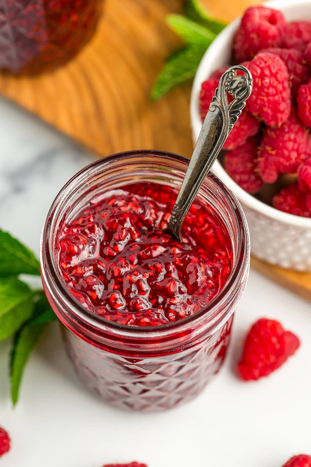 an open jar of raspberry jam with a spoon in it.