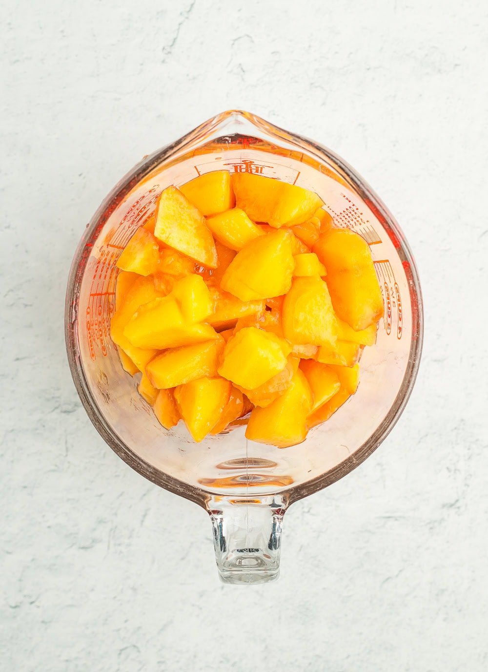 chunks of peaches in a measuring cup.
