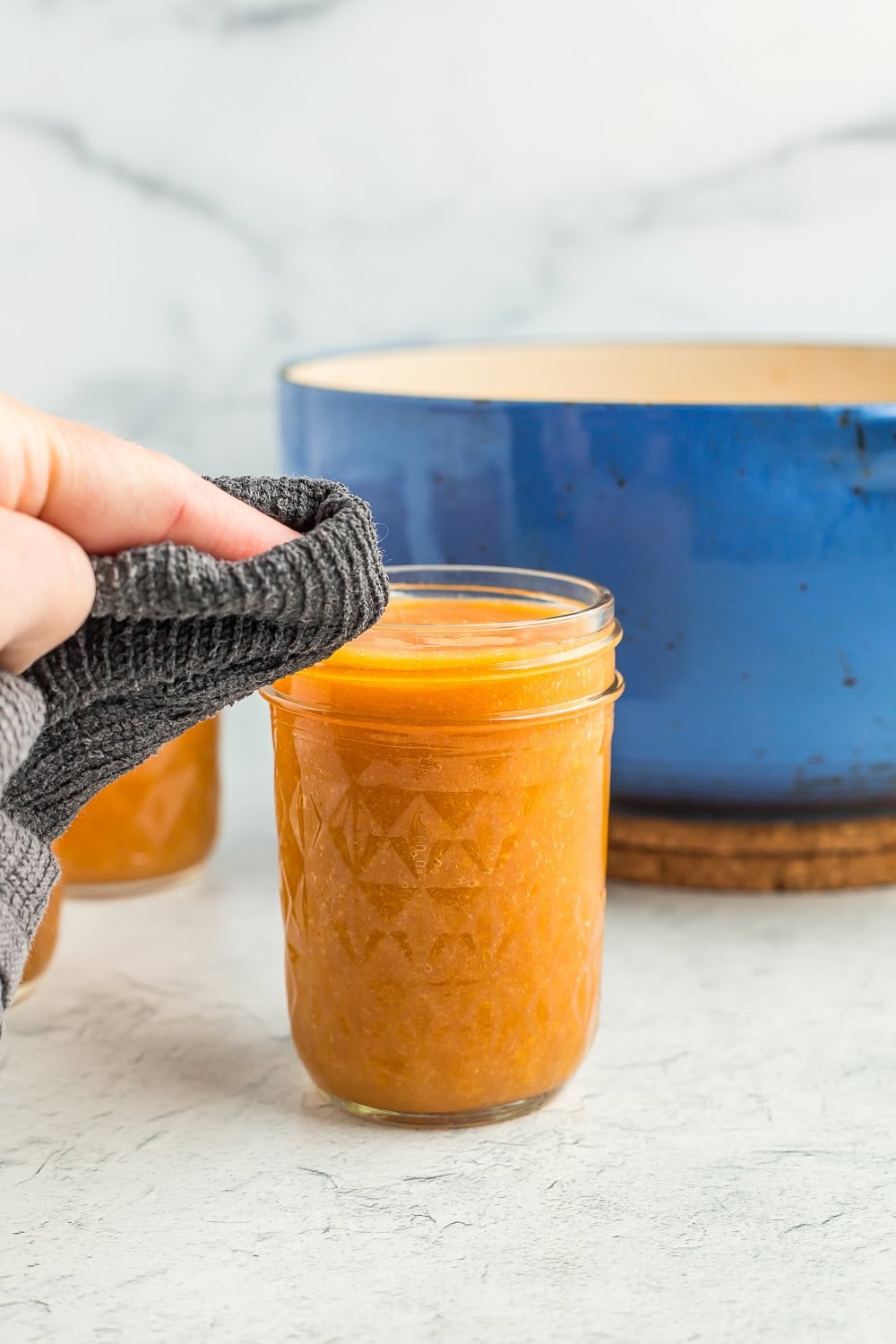 a rag wiping the rim of a canning jar.