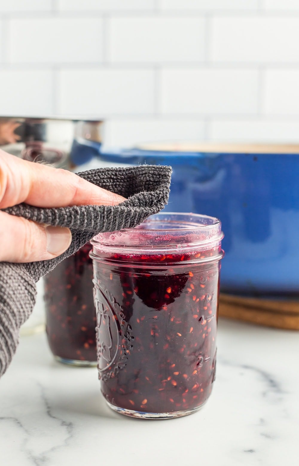 a rag wiping the rim of a canning jar.