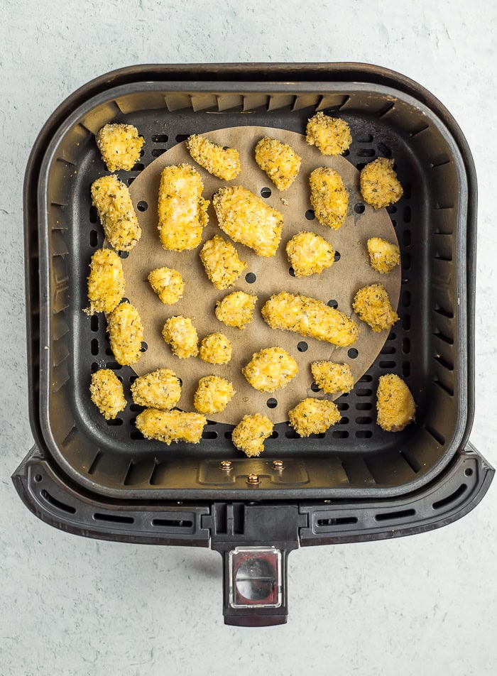 unbaked breaded cheese curds in an air fryer basket.