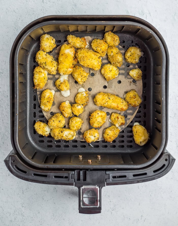 baked breaded cheese curds in an air fryer basket.