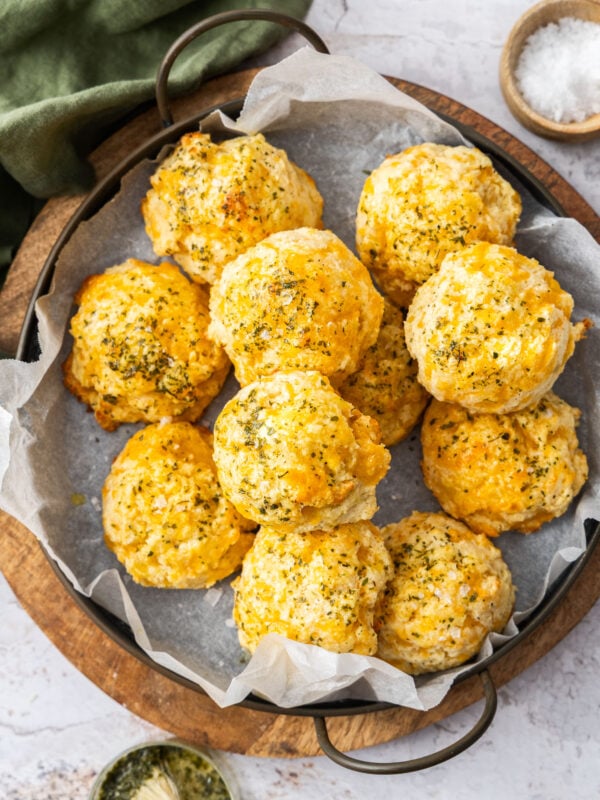 an overhead photo of a pan of cheddar bay biscuits on top of a wooden cutting board.