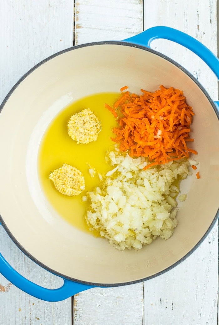 olive oil, carrots, garlic, and onion in a blue Dutch oven.