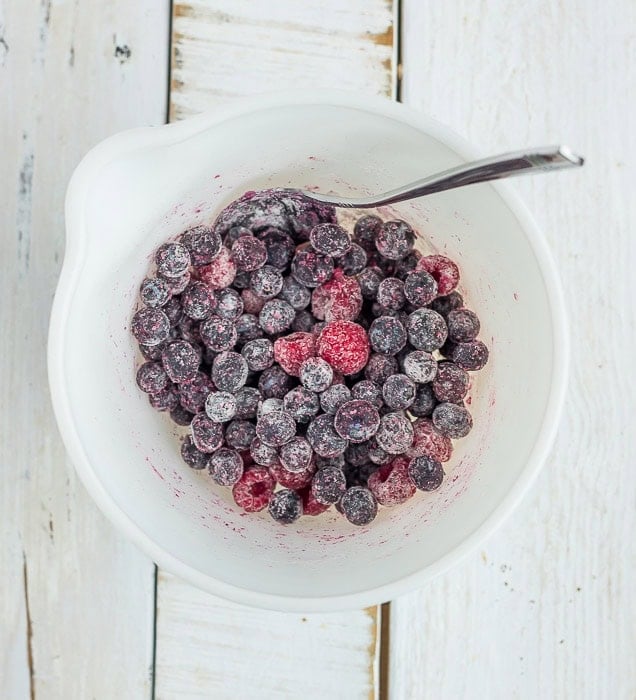 frozen berries tossed with all-purpose flour in a bowl.