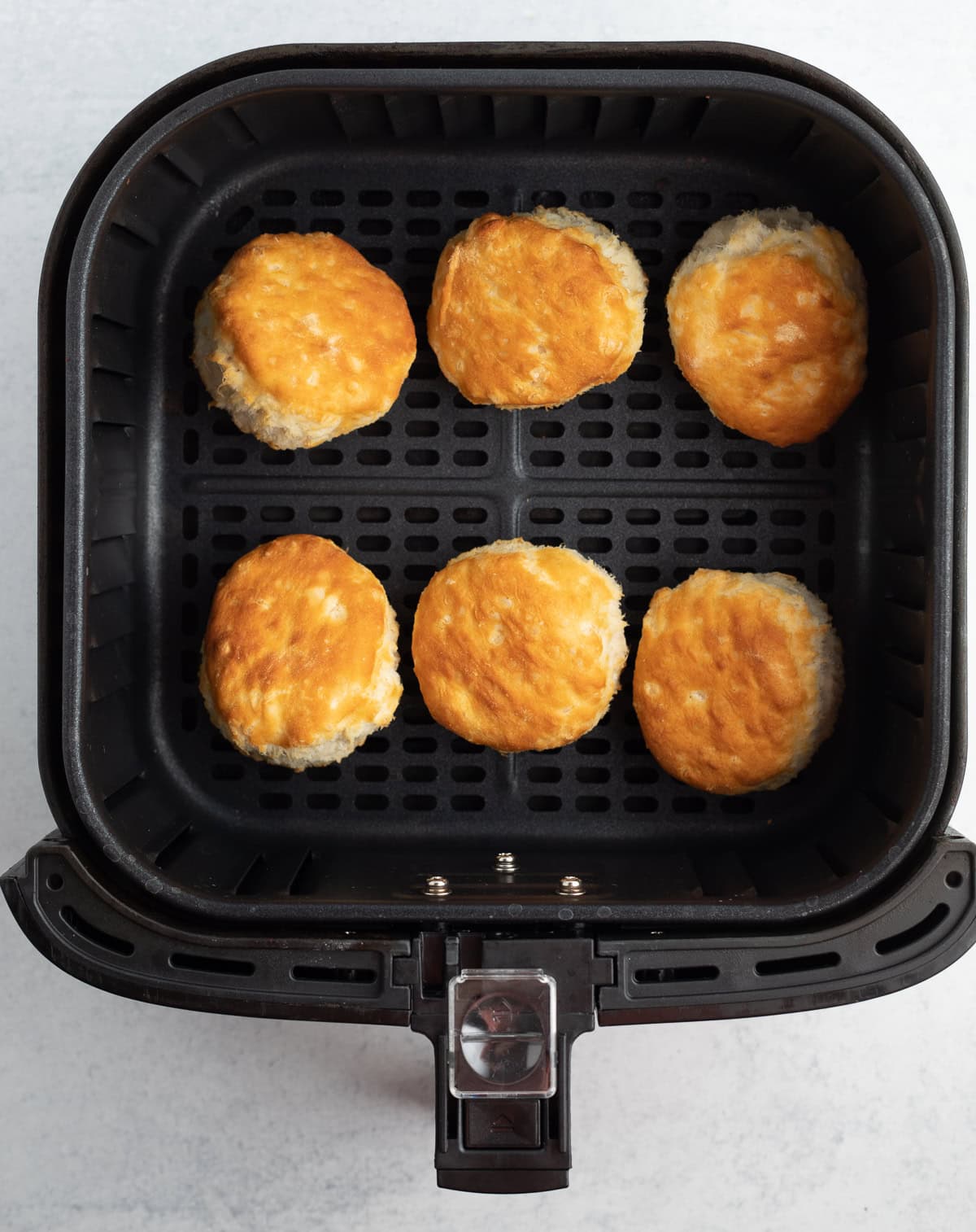 6 cooked biscuits in an air fryer basket.