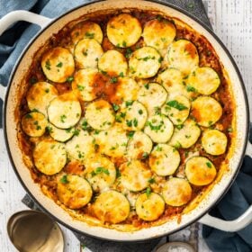 an overhead shot of a cheesy ground beef and zucchini casserole in a white skillet.