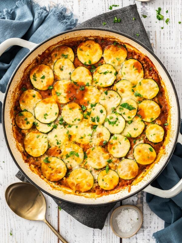 an overhead shot of a cheesy ground beef and zucchini casserole in a white skillet.