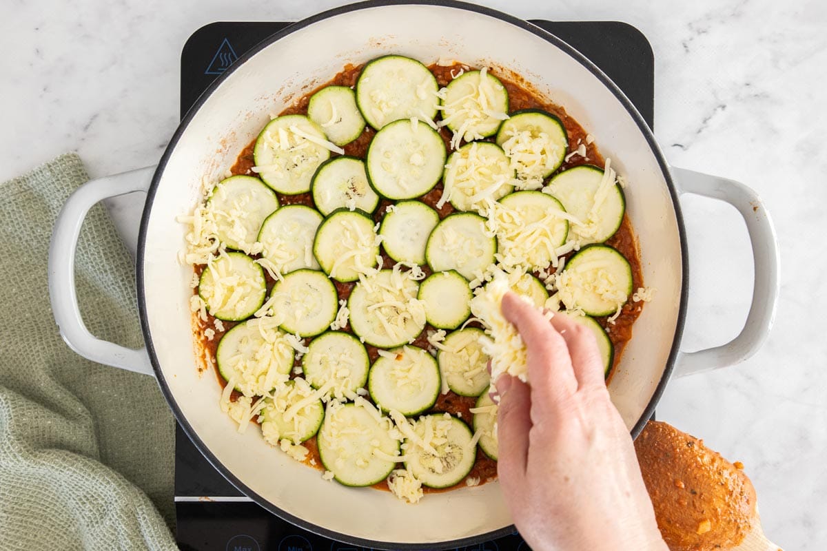 unbaked sliced summer squash and mozzarella in a white skillet.