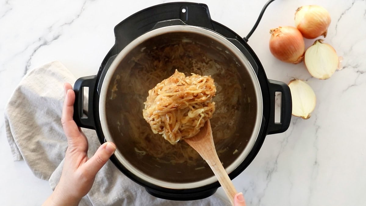 a spoon full of onions above a pressure cooker.