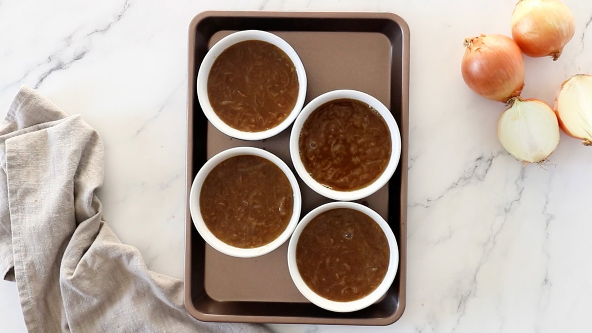 french onion soup in ramekins on a baking tray.