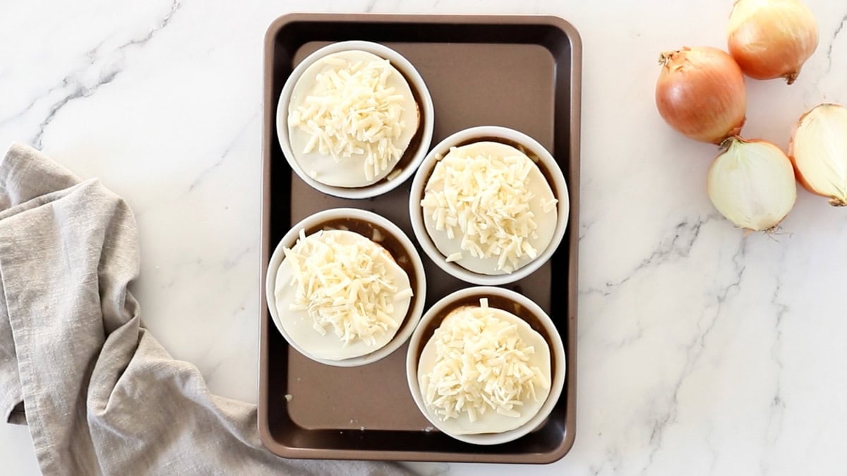 cheese on top of ramekins on a baking tray.