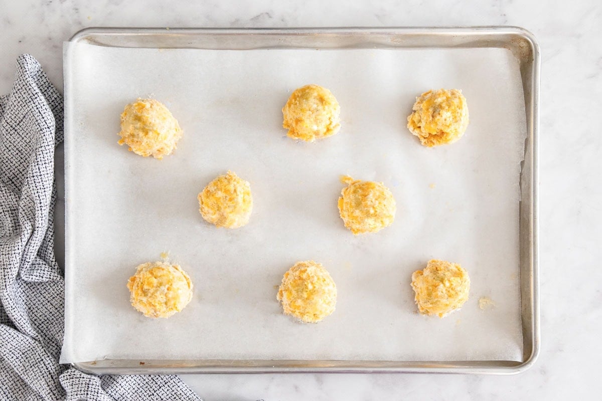 unbaked cheese rolls on a baking sheet.