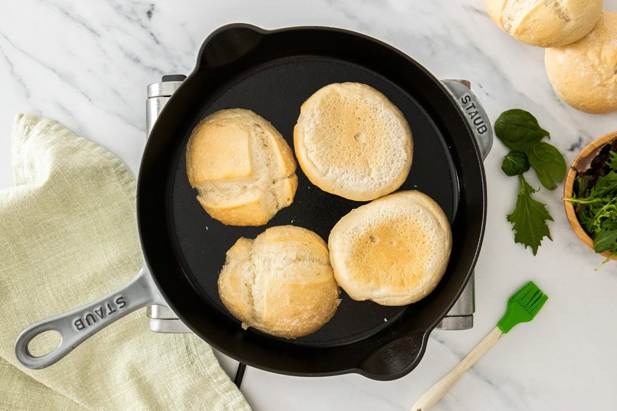 rolls being toasted in a cast iron skillet.