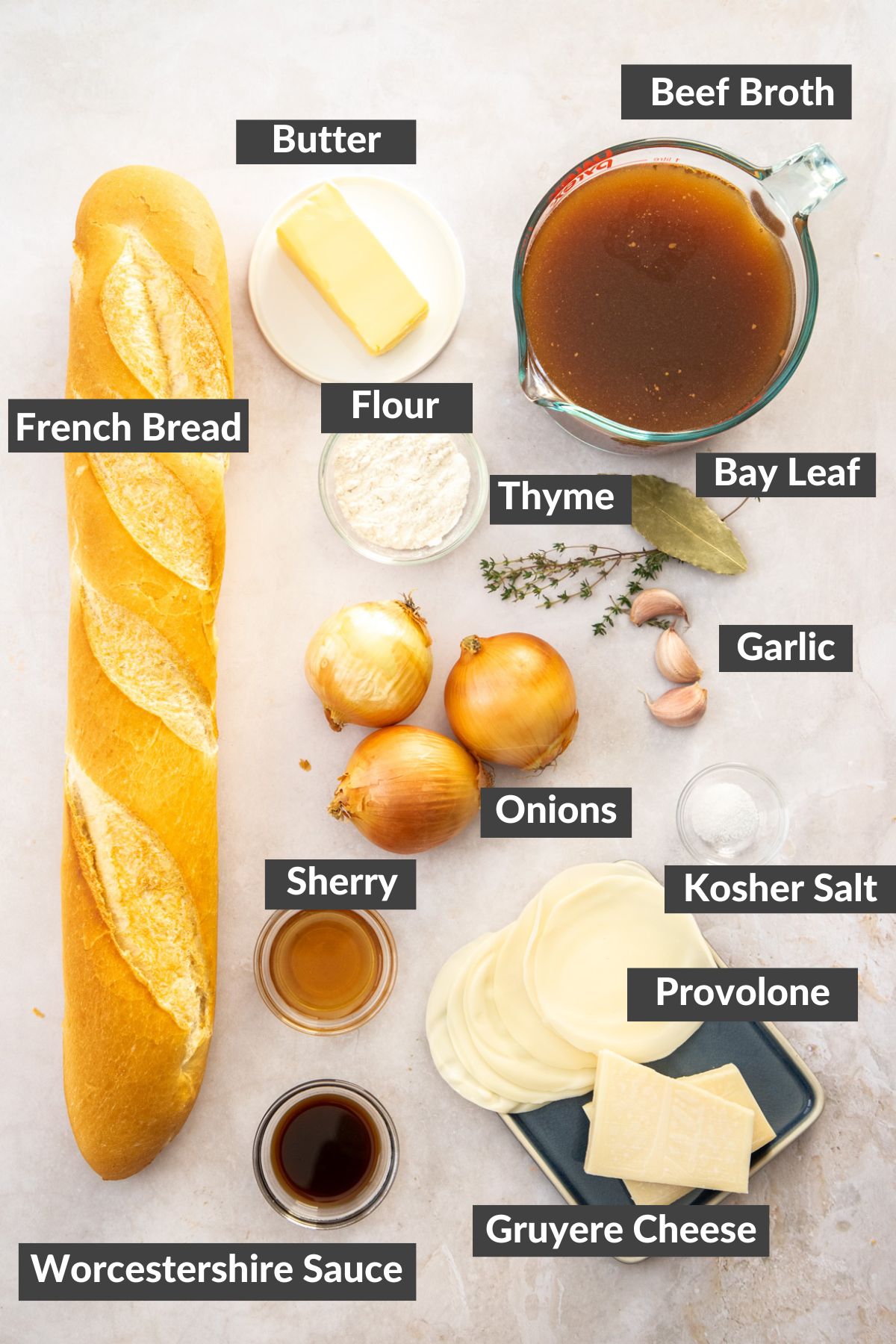 french bread, beef broth, onions, butter, and other ingredients on a tan board.