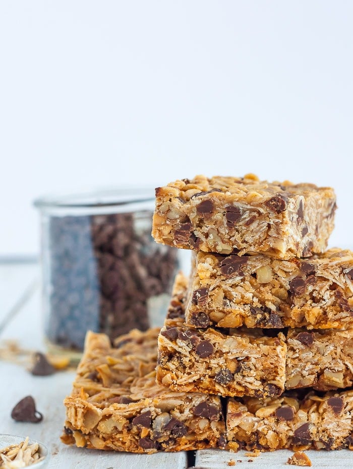 stacks of homemade granola bars in front of a small jar of chocolate chips.