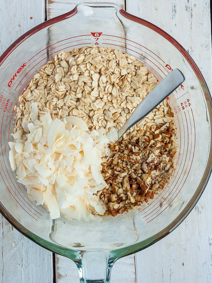 oats, nuts, and coconut flakes in a glass measuring cup.