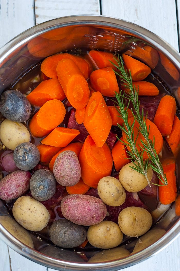 carrots, potatoes, and rosemary in a pressure cooker.