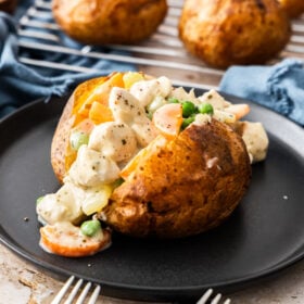 a split baked potato with chicken pot pie filling on it.
