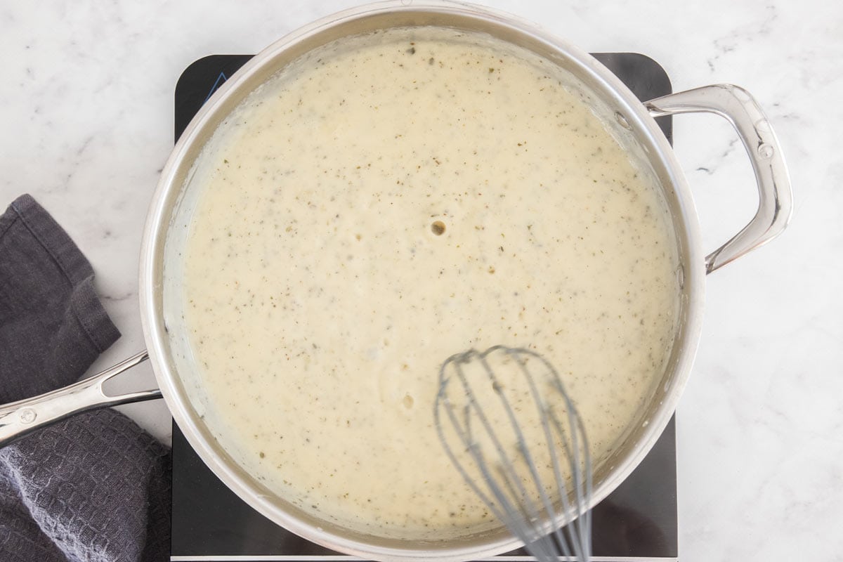 a homemade cream sauce and a whisk in a stainless skillet.