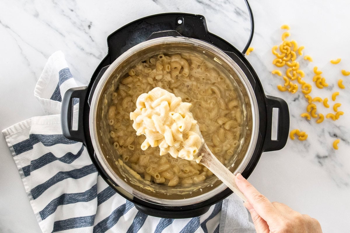 a spoon holding a scoop of mac and cheese over an Instant Pot.