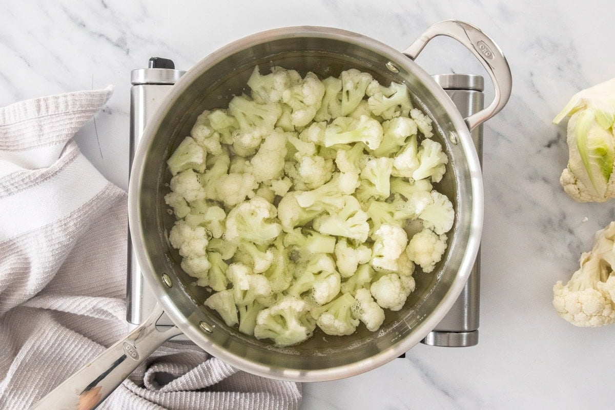 uncooked cauliflower florets in a stainless saucepan.
