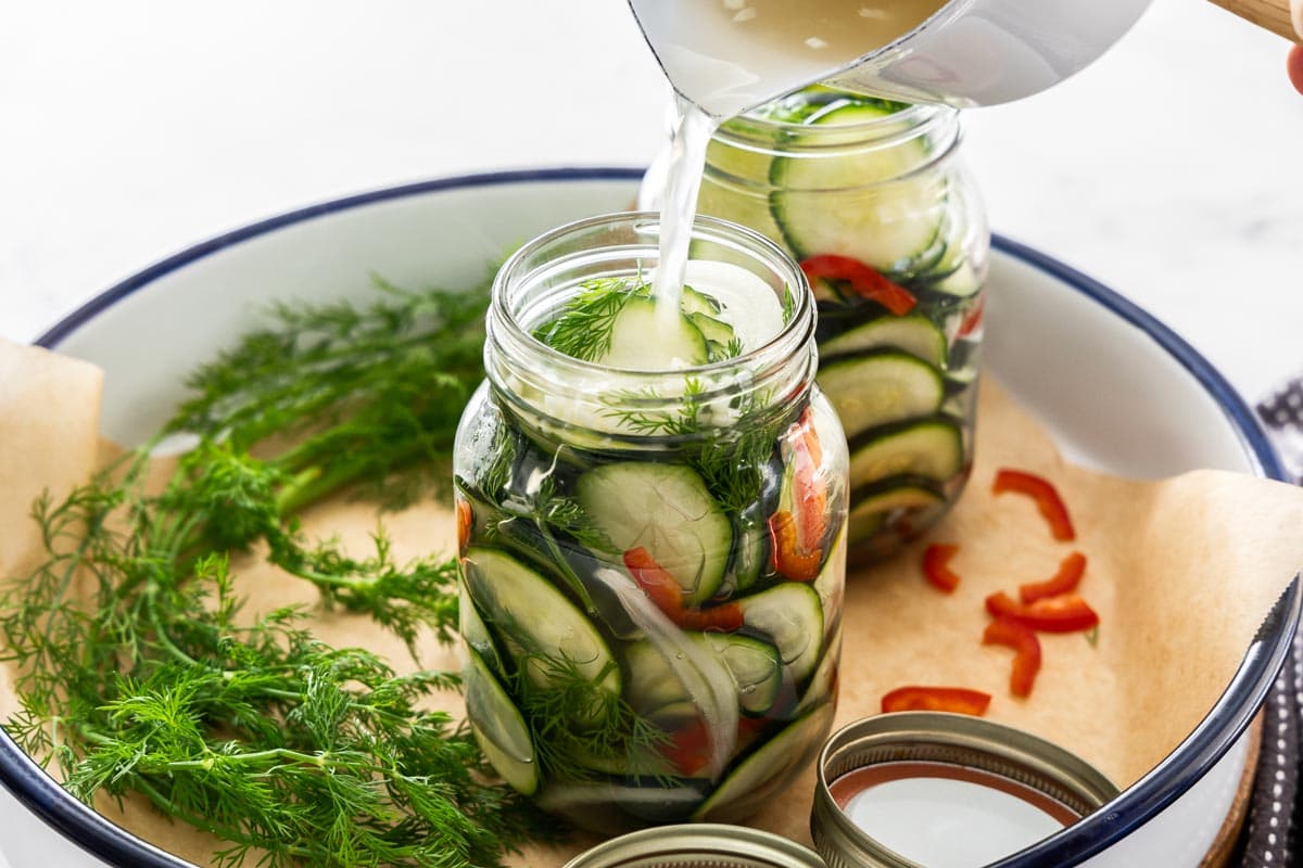 brine being poured into a jar full of ingredients.