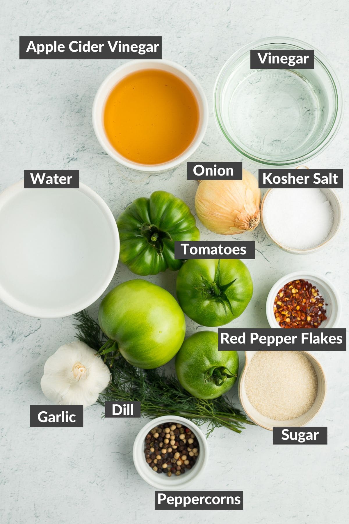 vinegar, garlic, dill, sugar, green tomatoes, and other ingredients on a board.