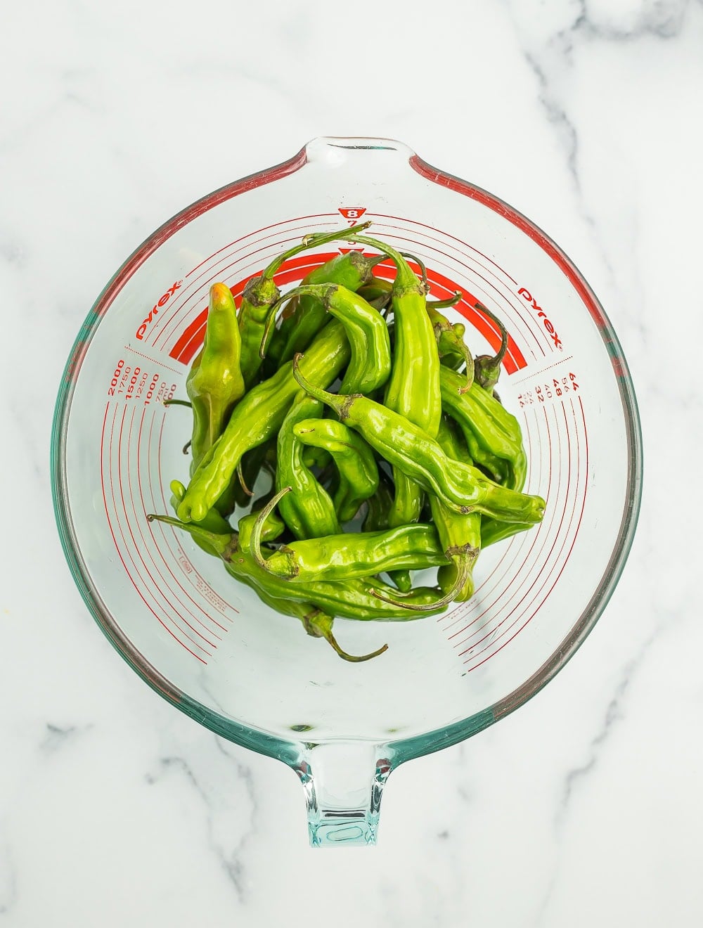 shishito peppers in a glass bowl.