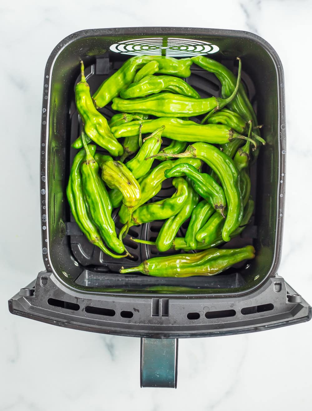 an air fryer basket with peppers.