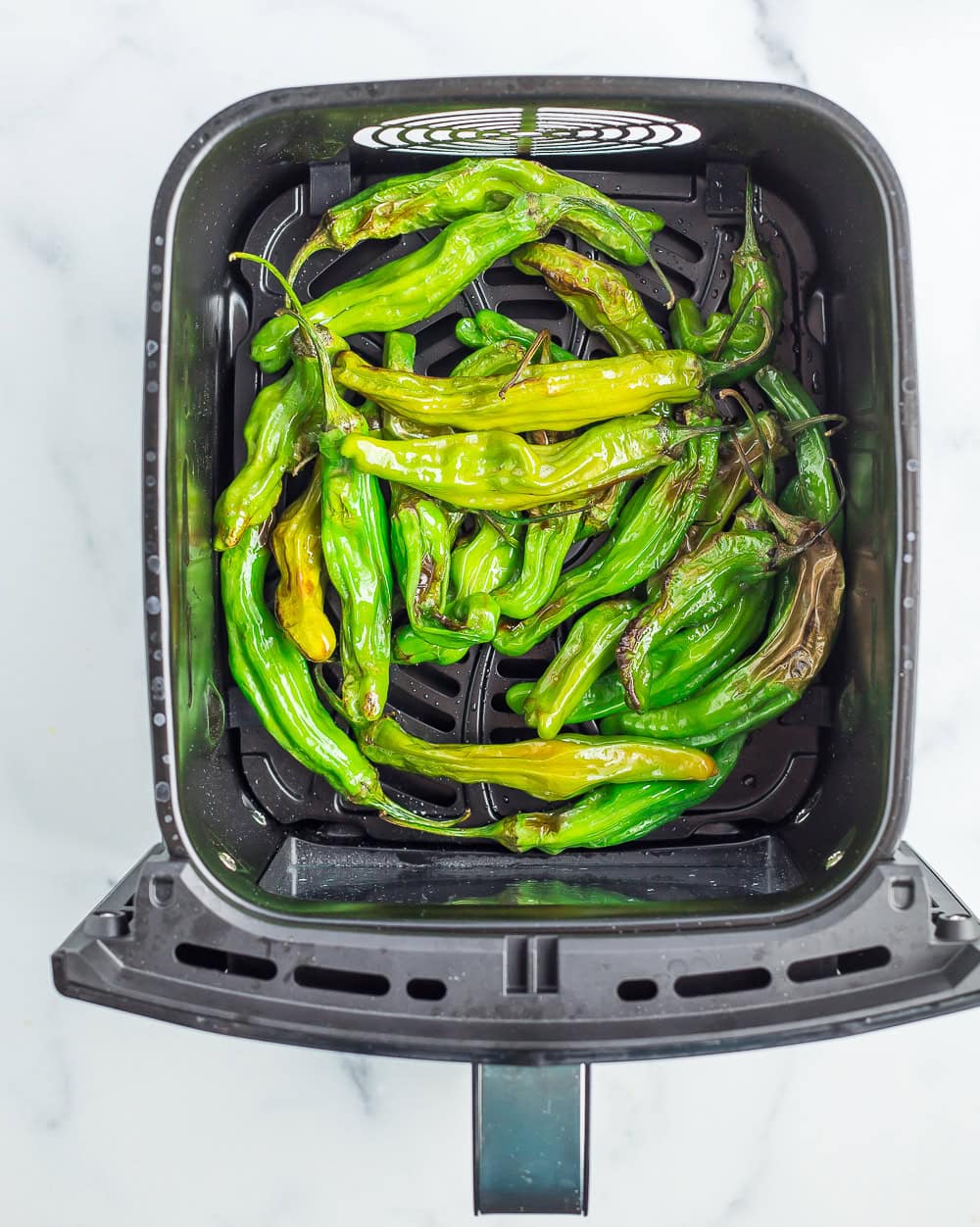 an air fryer basket with partially cooked peppers.