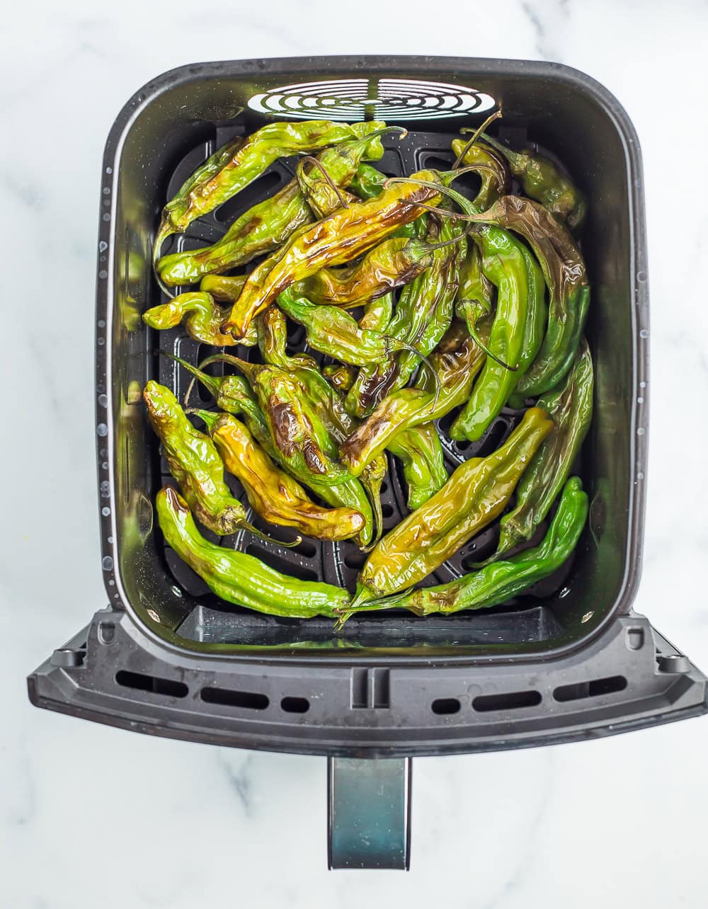 an air fryer basket with cooked peppers.
