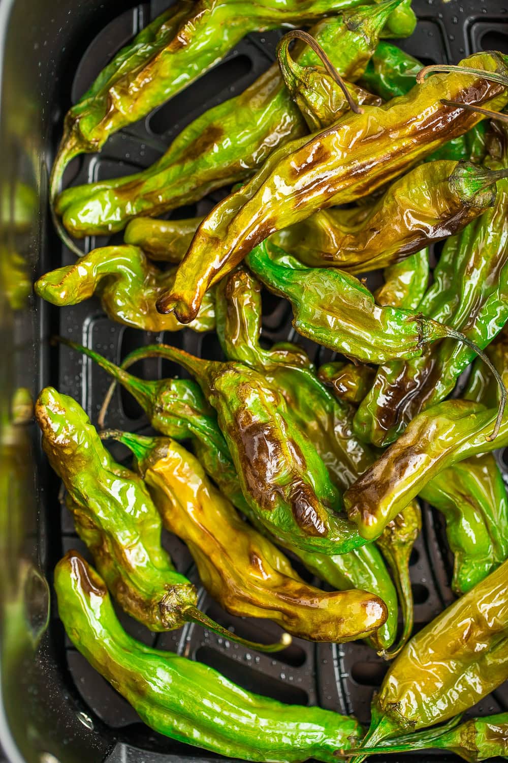 an air fryer basket with blackened peppers.