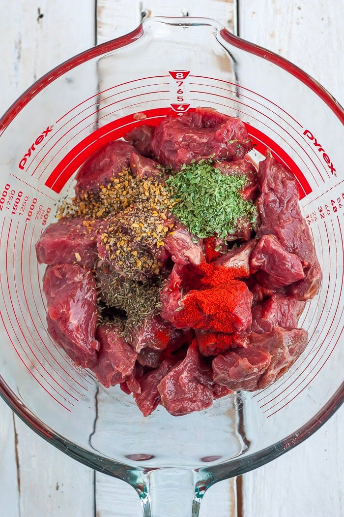 seasonings and beef in a glass bowl.