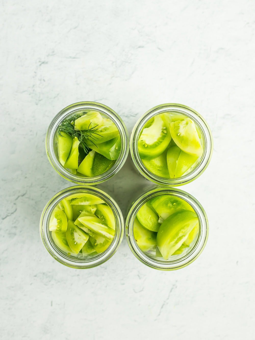 sliced green tomatoes in 4 jars.