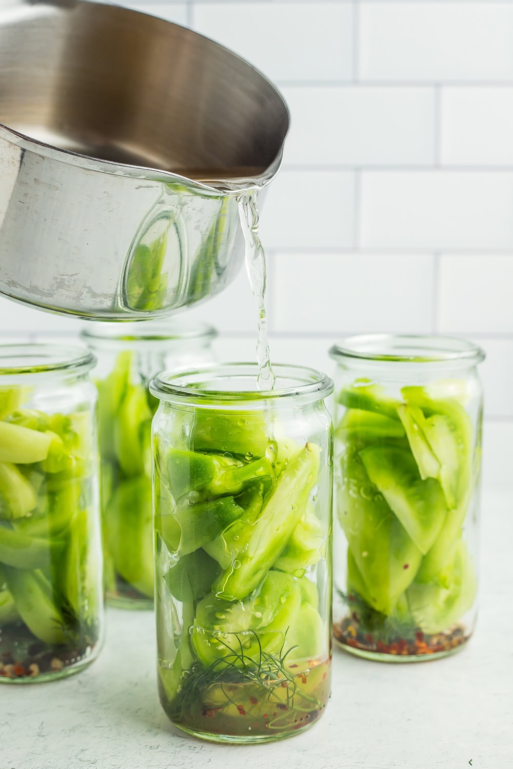 a saucepan pouring brine into canning jars.