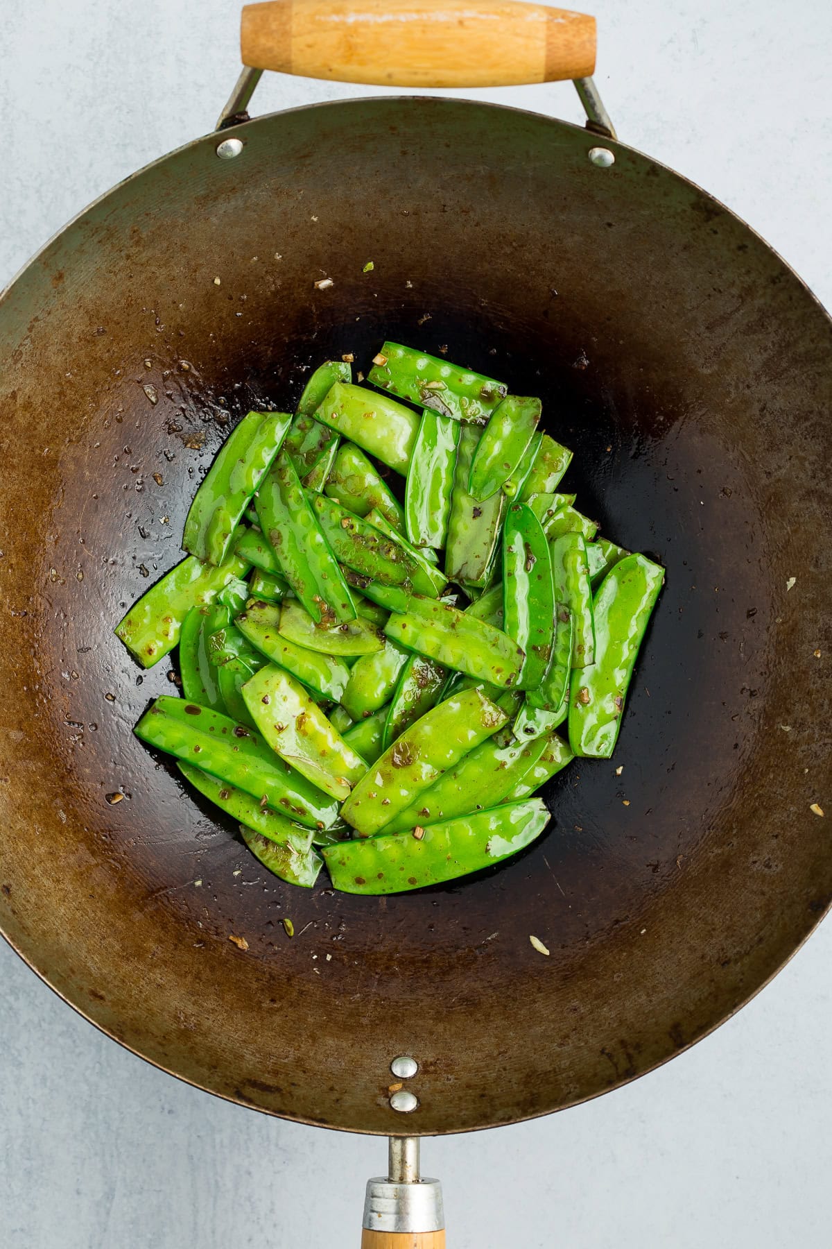 stir fried snow peas in a wok.
